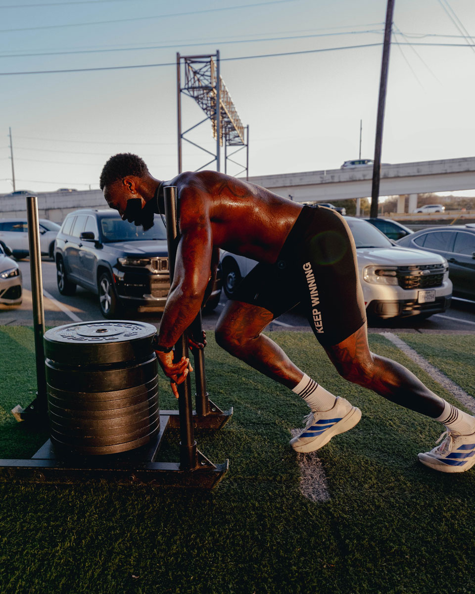 Coach performing strength training exercise in a gym setting.